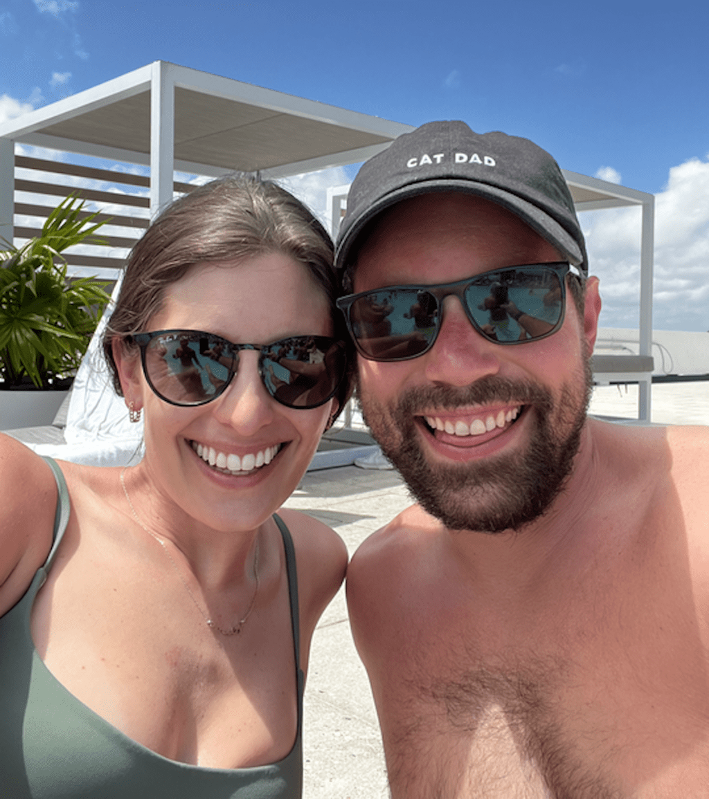 man and woman posing poolside with cabana 