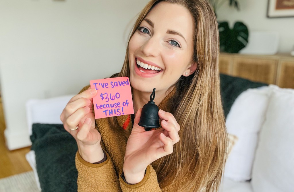 woman holding menstrual cup with post it note savings