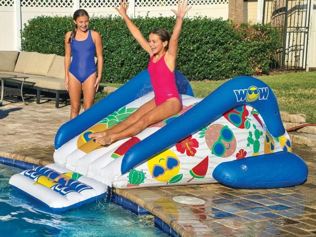 kid sliding down inflatable fruit slide into pool