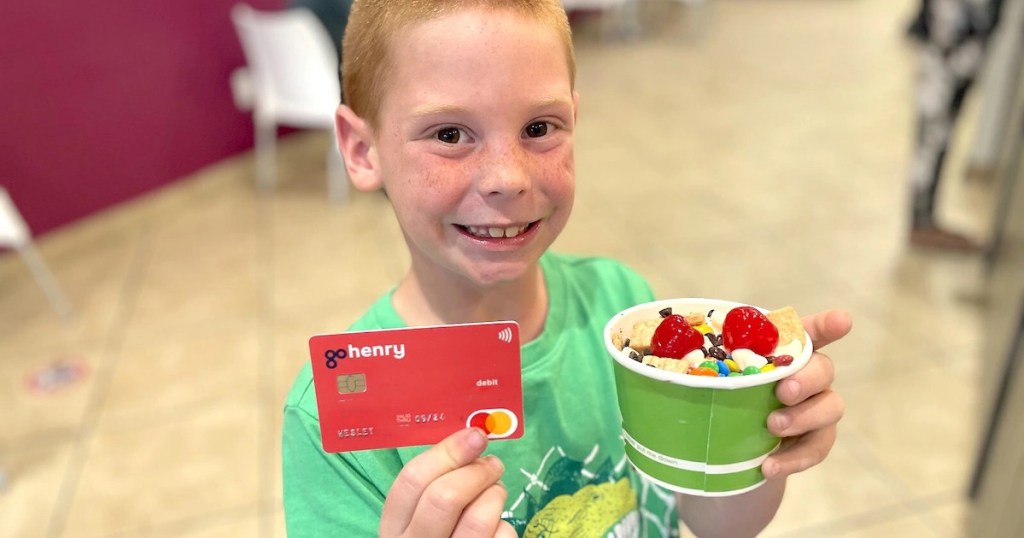 young boy holding gohenry debit card for kids