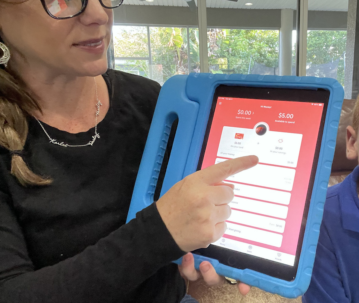 woman holding up ipad with gohenry app 