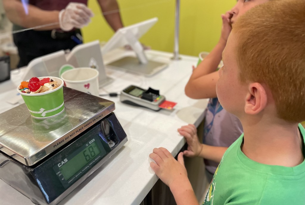 boy standing at sweet frog register paying for ice cream