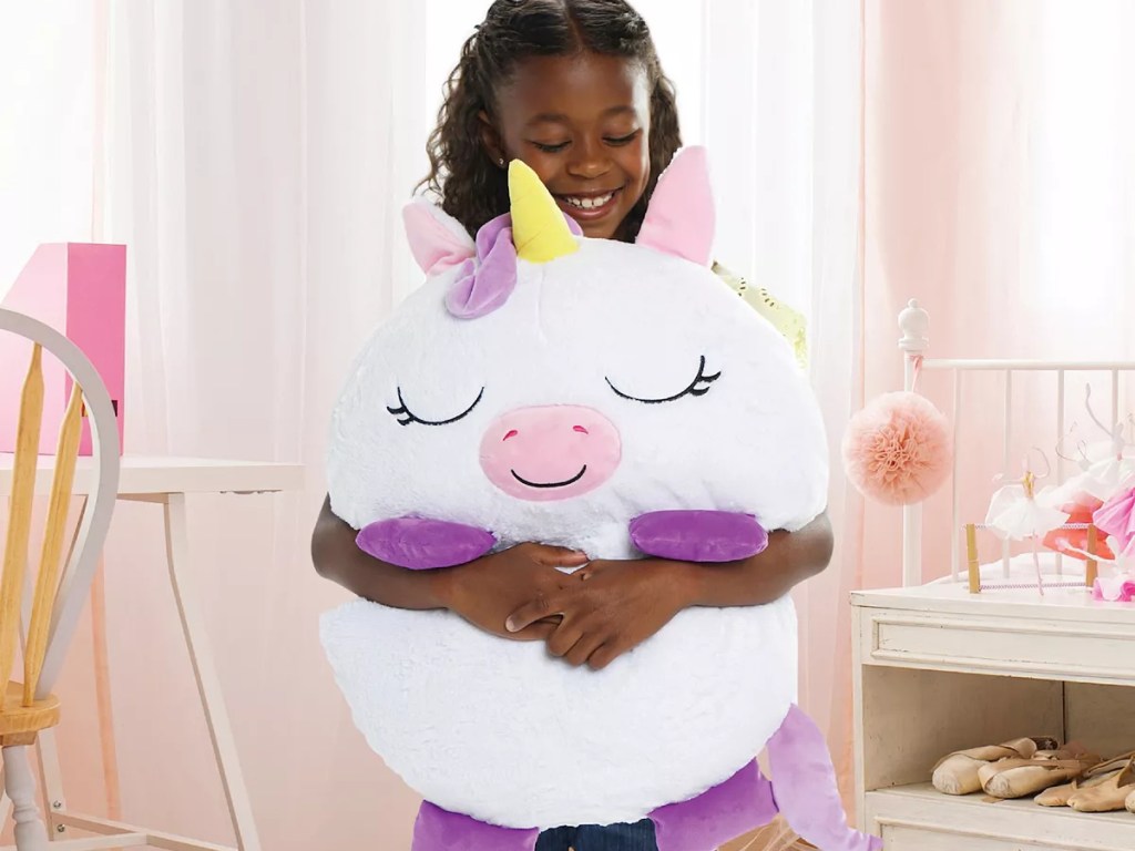 girl hugging a happy napper unicorn pillow