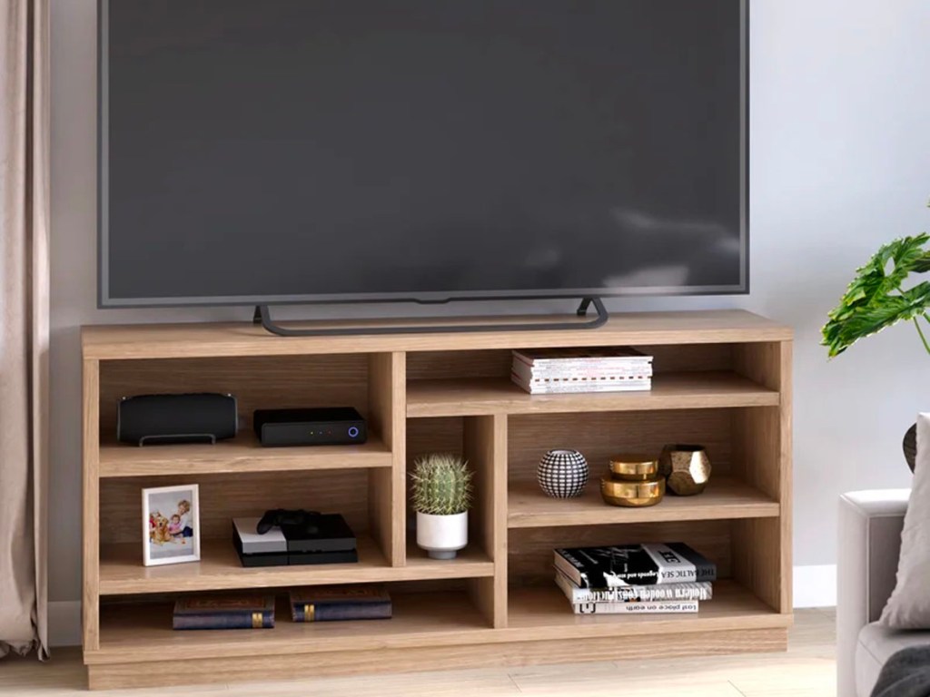 light brown tv stand with tv, decor, books and dvd player on it