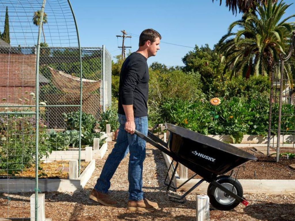 man using green Husky Wheelbarrow
