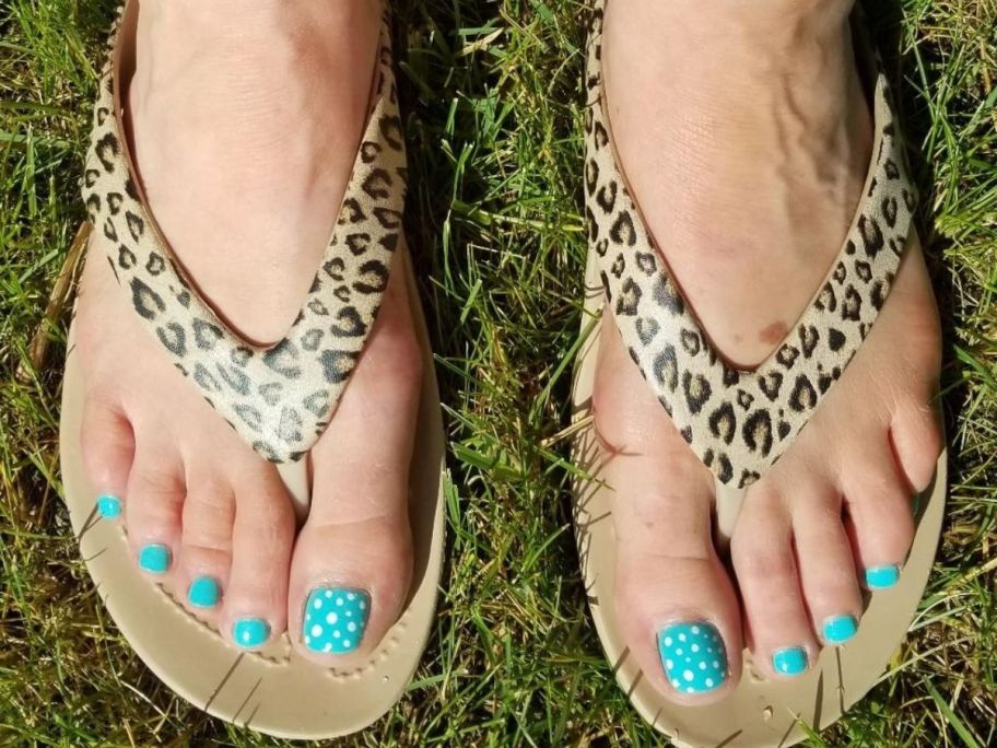 woman with blue toenails wearing leopard print flip flops