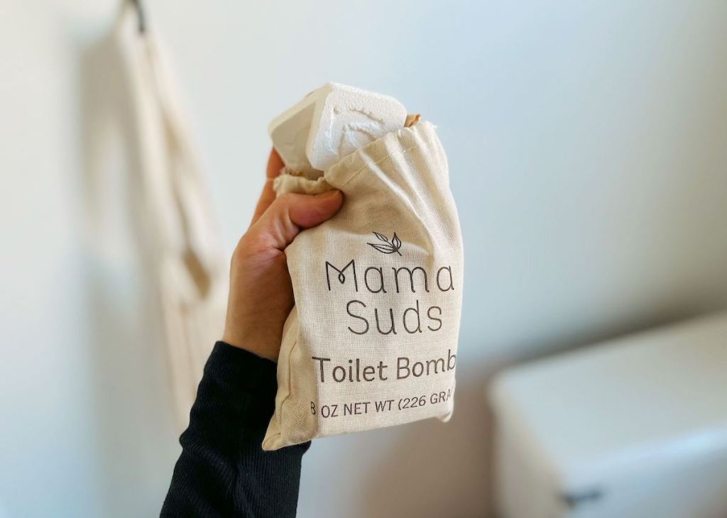 hand holding mama suds toilet bombs in bathroom