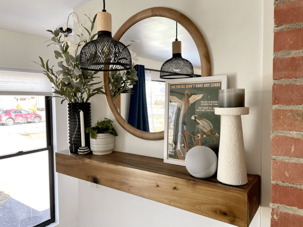 mantel on wall with various home decor and round mirror