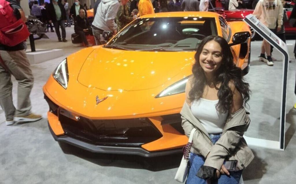 woman posing with yellow sports car at auto show