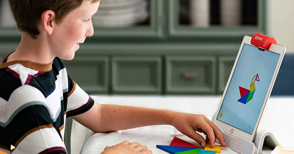 preteen boy sitting at table playing ipad game