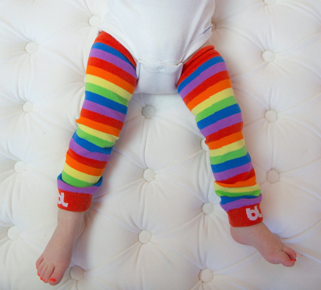 baby legs wearing rainbow leggings on tufted white coffee table