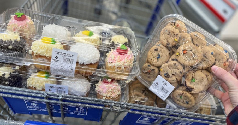 shopping cart filled with packs of deli cupcakes and cookies