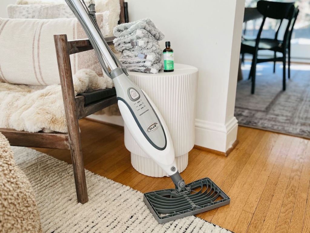 shark steam mop vacuum leaning on chair with extra pad and bottle of essential oils
