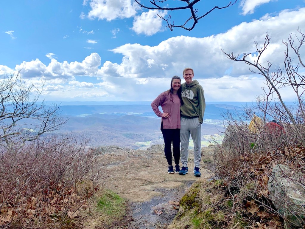 man and woman posing on top of mountain smiling