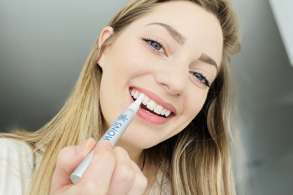 woman with whitening pen on teeth