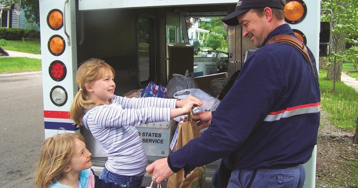girls donating food to a letter carrier