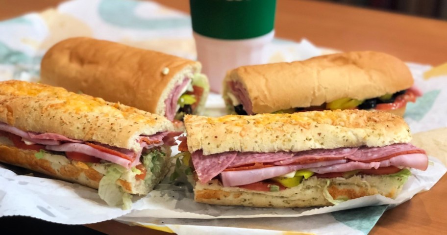 two subway sub sandwiches with a soda