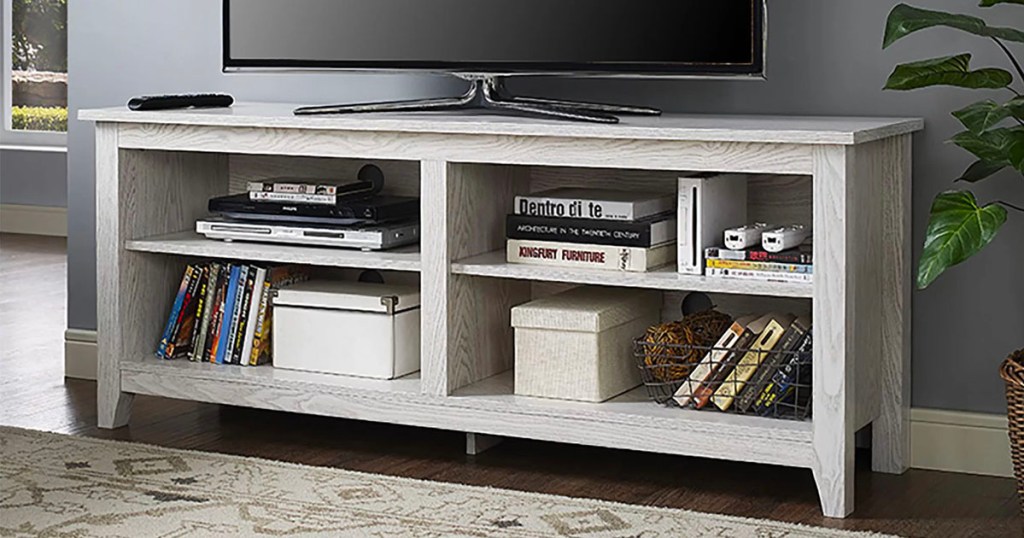white tv stand with tv on top and books on shelves