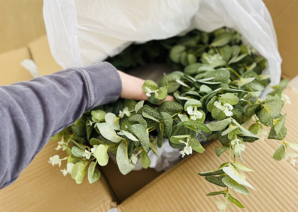 hand pulling green eucalyptus wreath from walmart home decor box