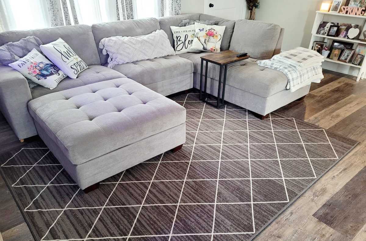 gray sectional with darker gray diamond rug in living room