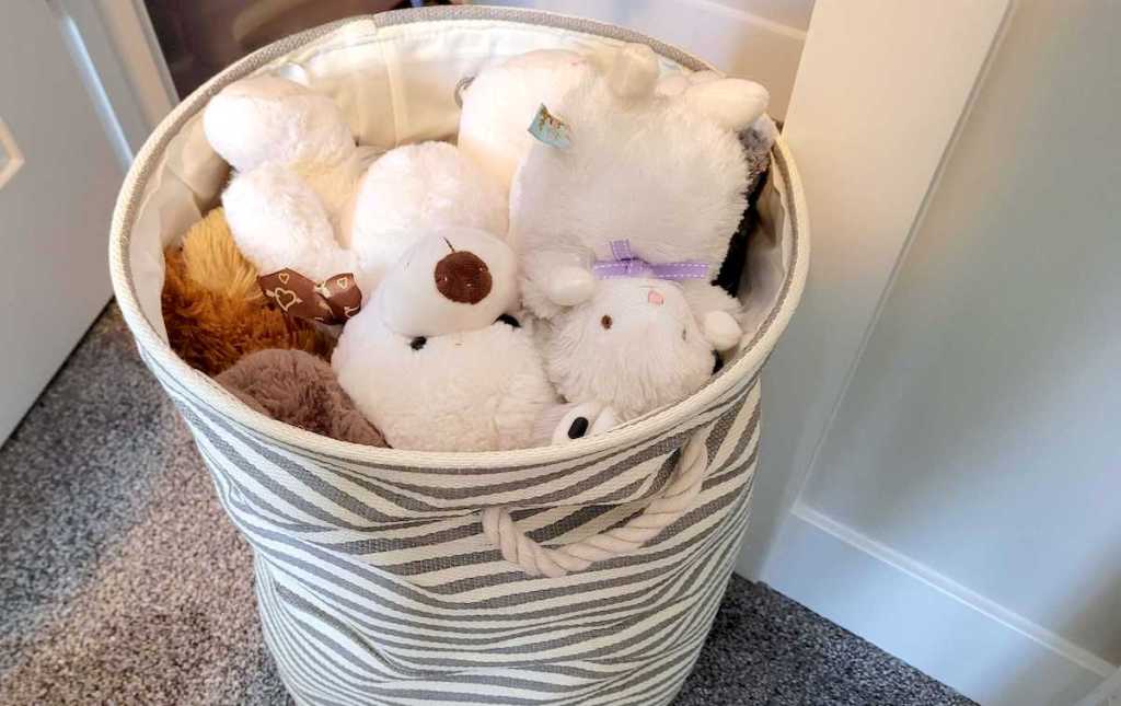 canvas bin with stuffed animals piled inside