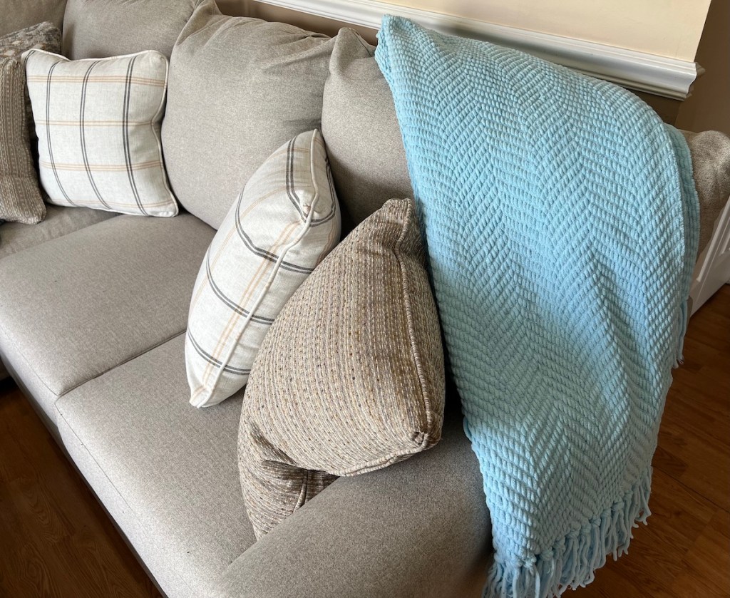 light blue tweed blanket on gray couch with throw pillows
