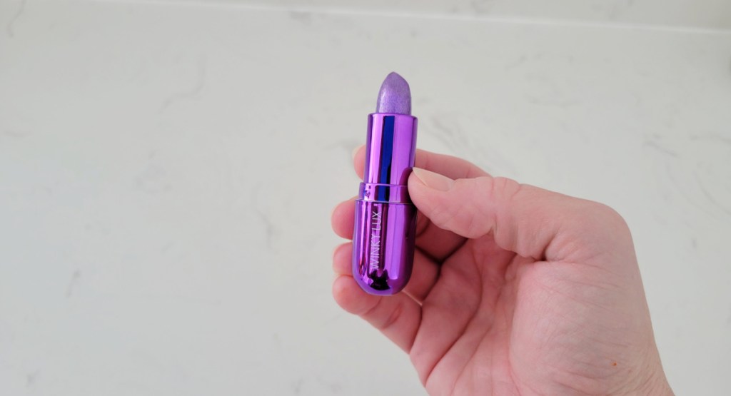 hand holding purple lipstick