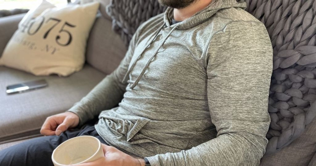 man sitting on couch wearing cool long sleeve hooded shirt