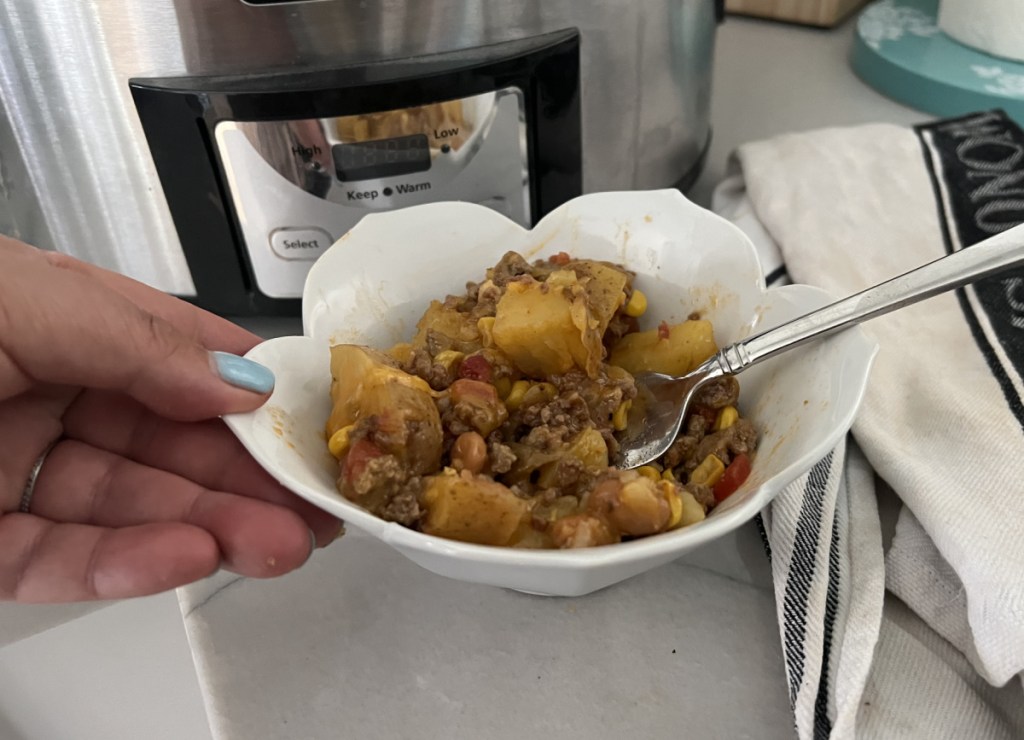 Hand holding a bowl of slow cooker Cowboy Supper