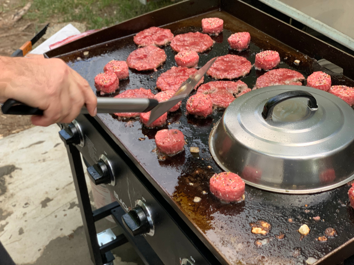 flat grill with hamburgers cooking on it