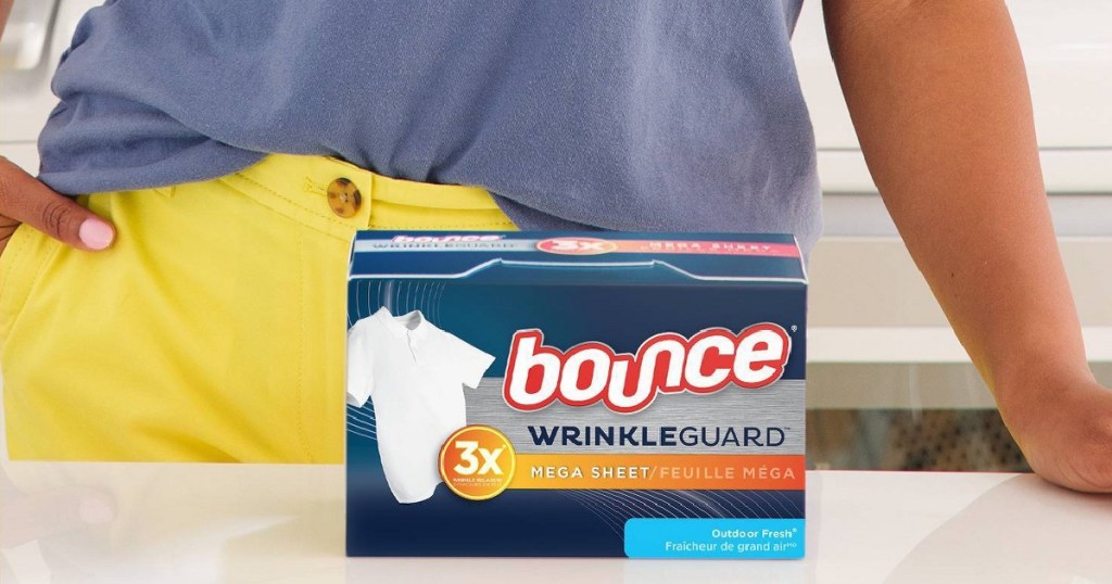 woman in yellow pants standing behind a box of bounce wrinkleguard dryer sheets