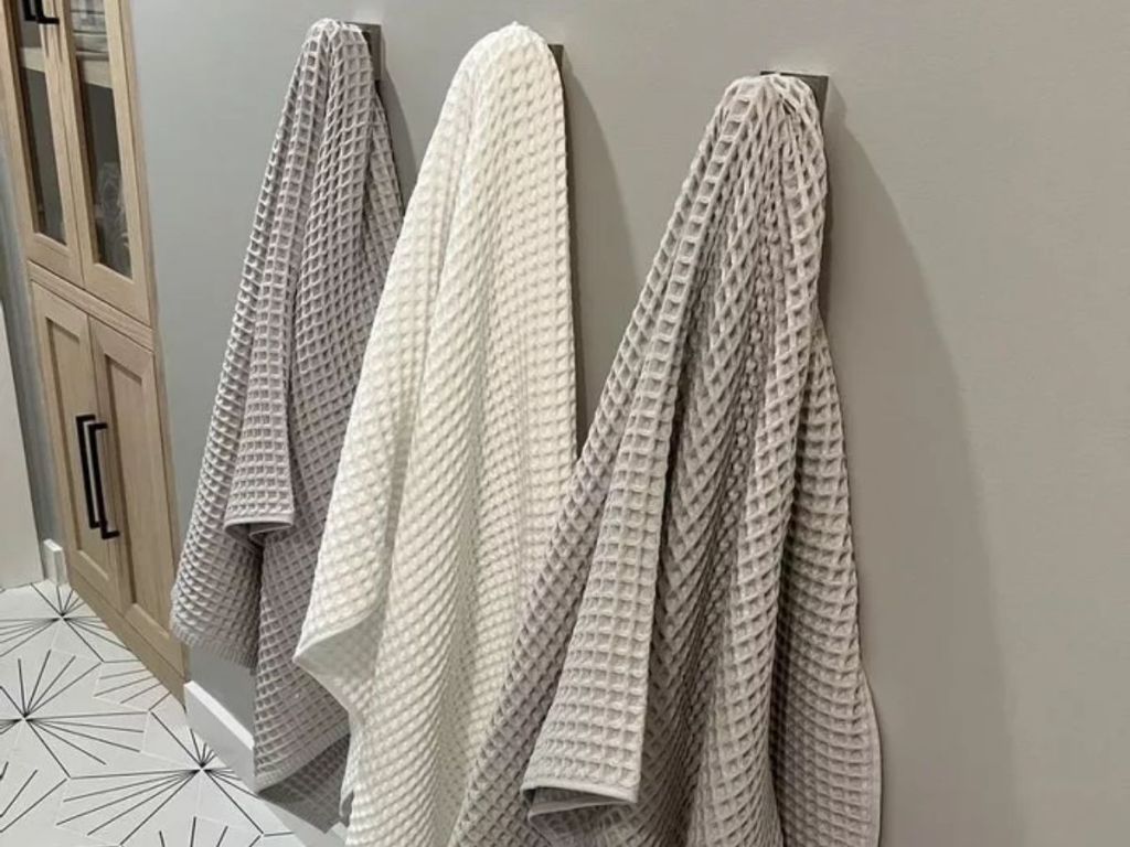 3 waffle bath towels on hooks in bathroom