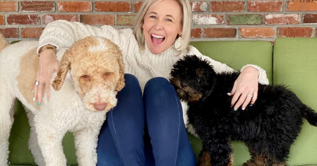 woman laughing on couch surrounded by 2 dogs