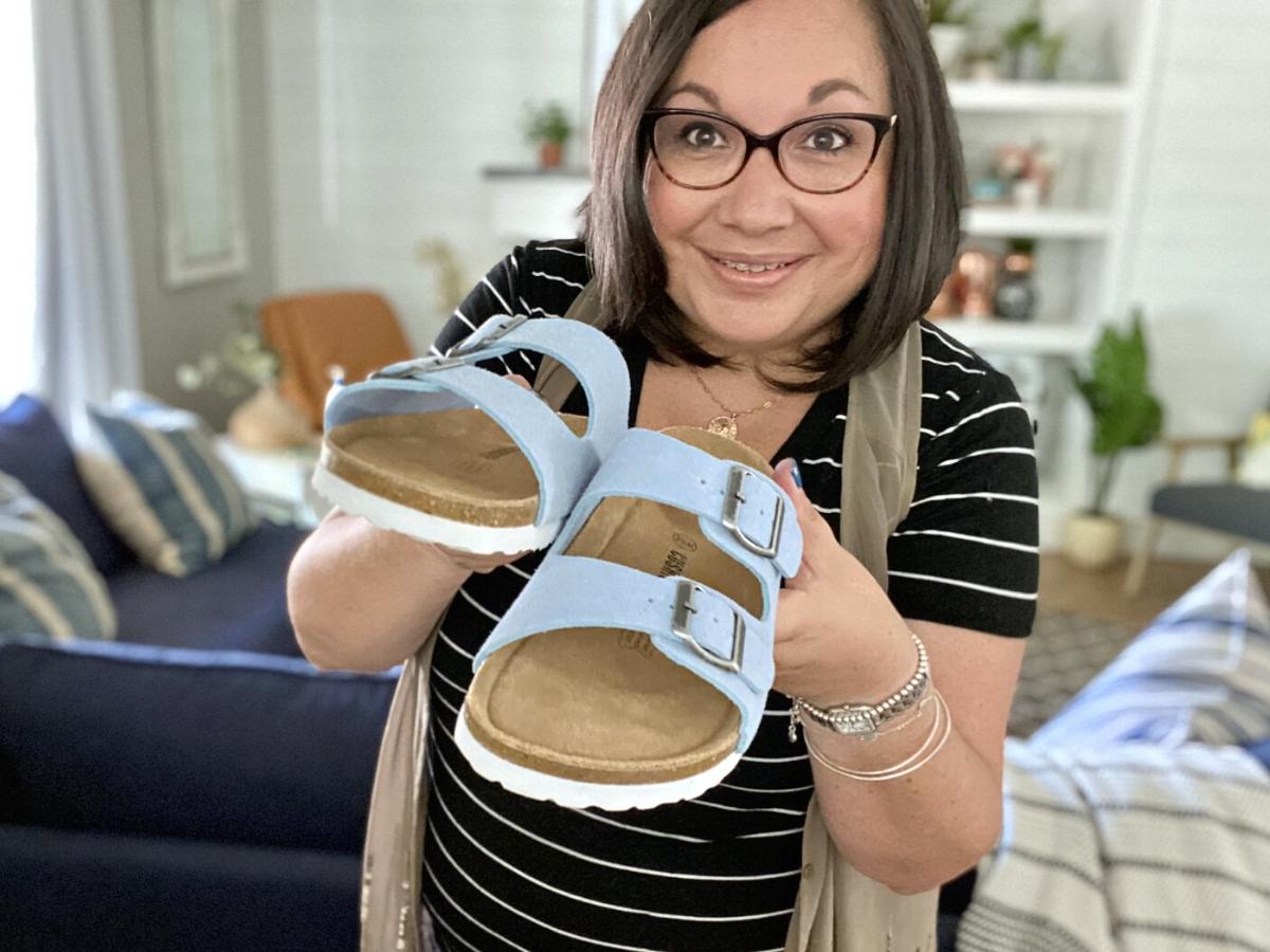 woman holding blue Cushionaire Lane Sandals in hand