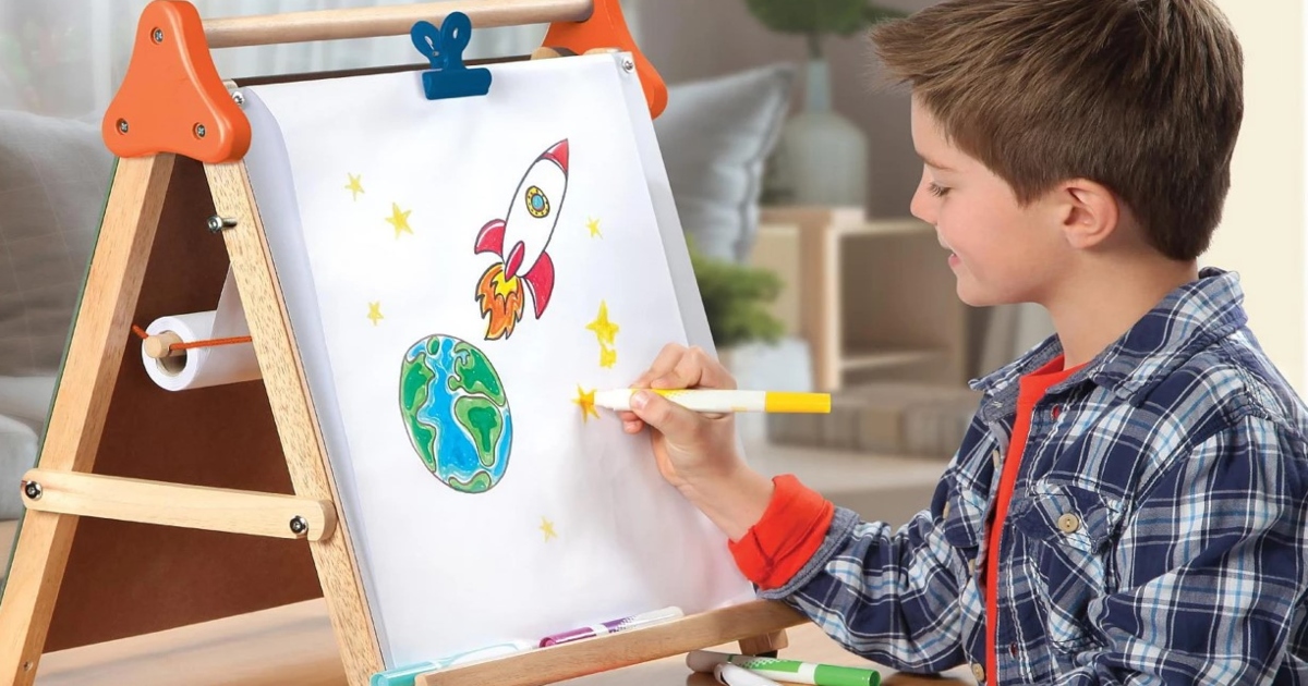 Boy at a desk drawing on a tabletop dry erase Easel