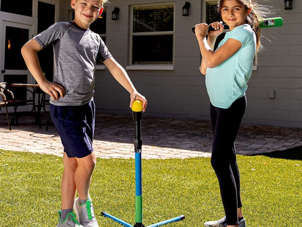 Two kids standing next to a batting tee