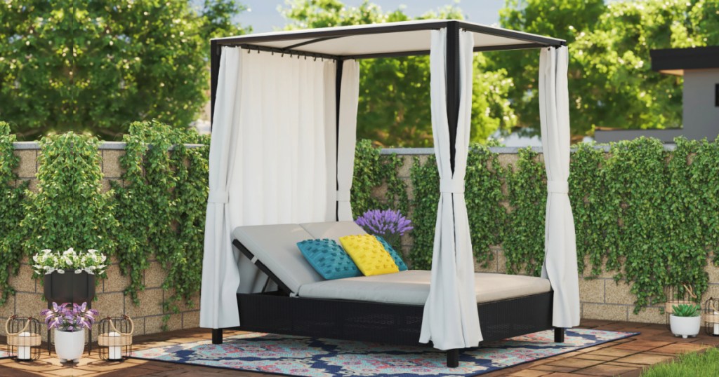 black steel Gazebo with double chaise lounge in white cushions outside in yard