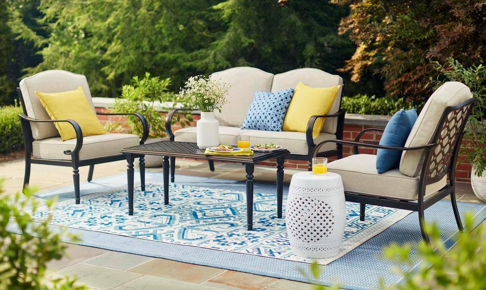 Metal patio set with tan cushions on a blue rug outside