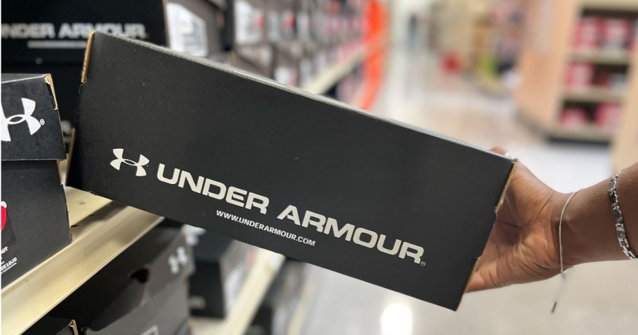 Hand grabbing UA box of shoes of shelf