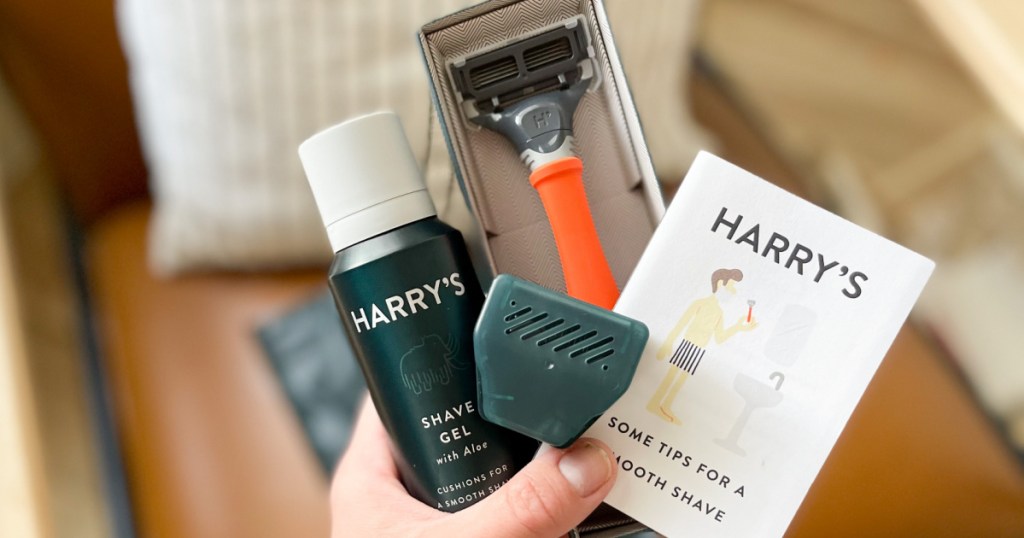 hand holding a Harry's Razor Shaving Kit with a razor, shave gel, travel case and guide