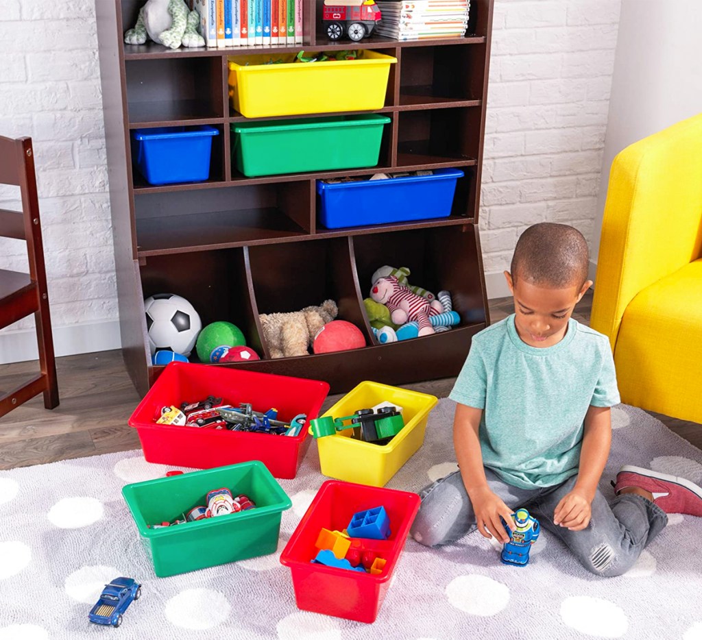 boy playing on floor with toys in colorful bins