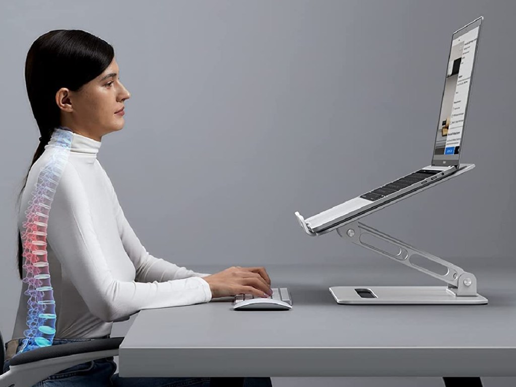 laptop on riser and woman typing at desk