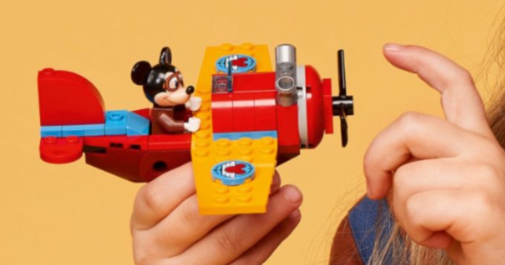 Girl holding Lego Mickey Mouse plane