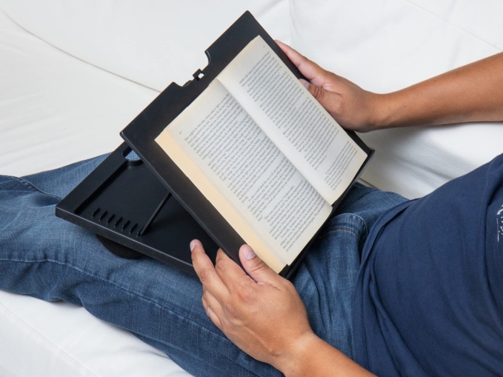 man reading from book sitting on lap desk