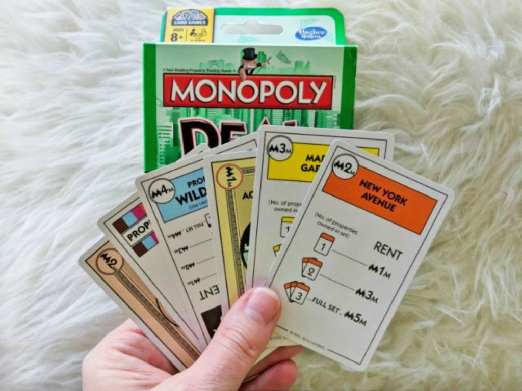 hands holding cards to Monopoly Deal game