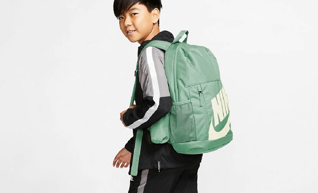 boy walking with green backpack