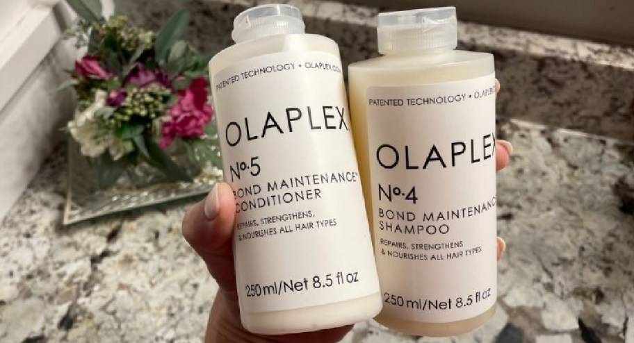 A hand holding Olaplex Shampoo and Conditioner