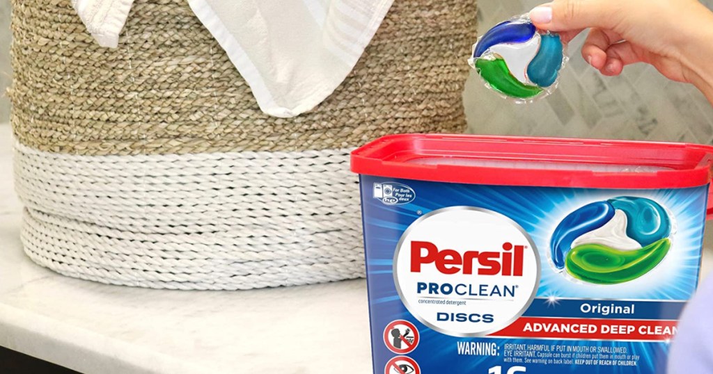 Persil Discs Laundry Detergent Pacs in woman's hand with bucket in front of her