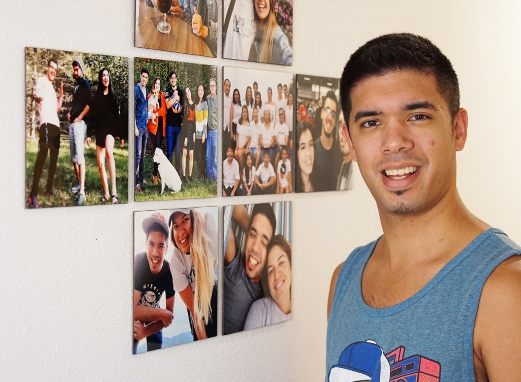 man standing next to photo gallery wall
