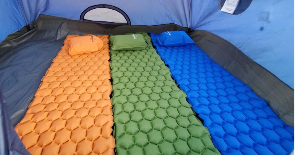 three sleeping mats side by side on tent floor